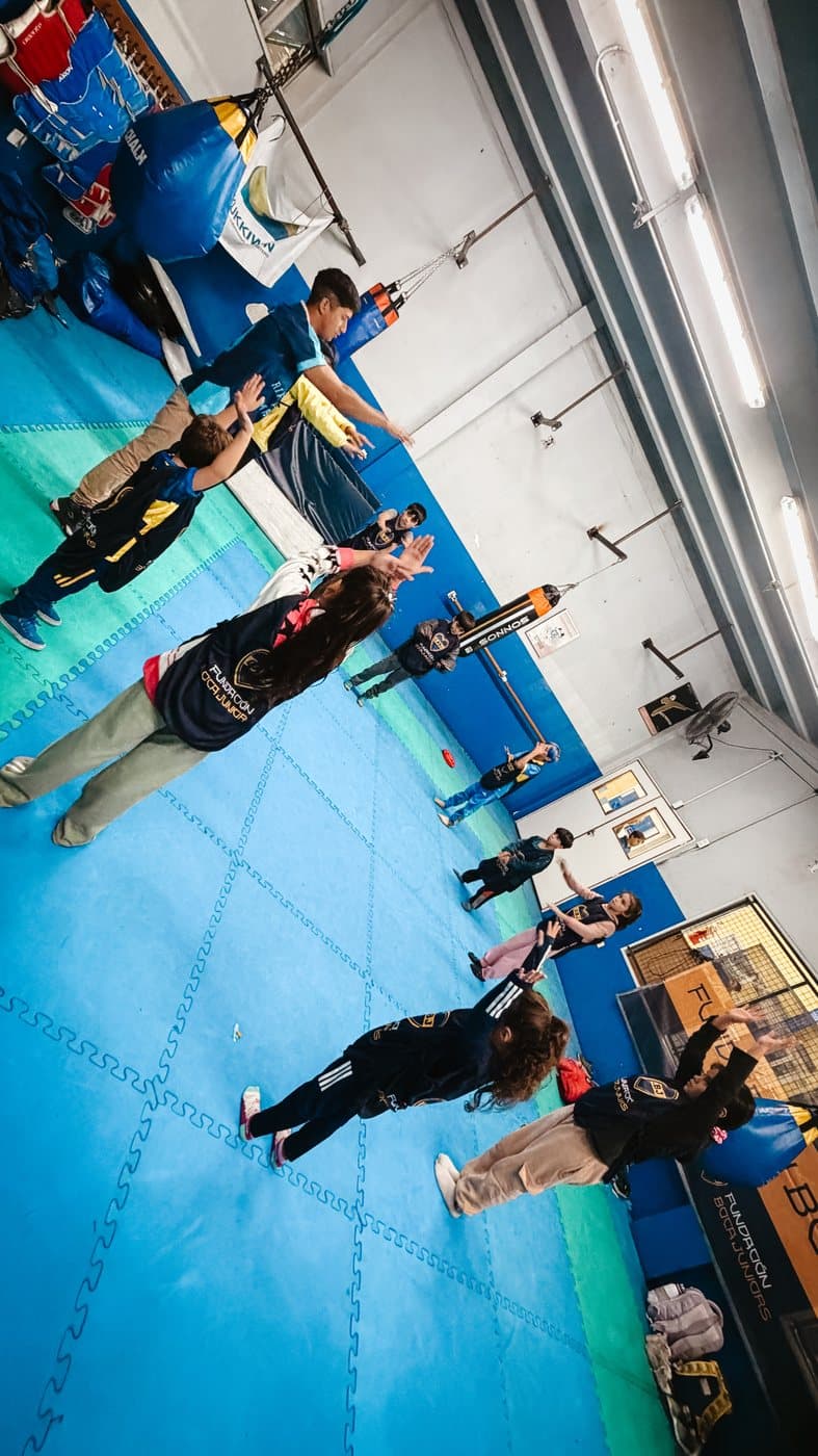 Chicos y chicas ejercitando en el gimnasio de boxeo