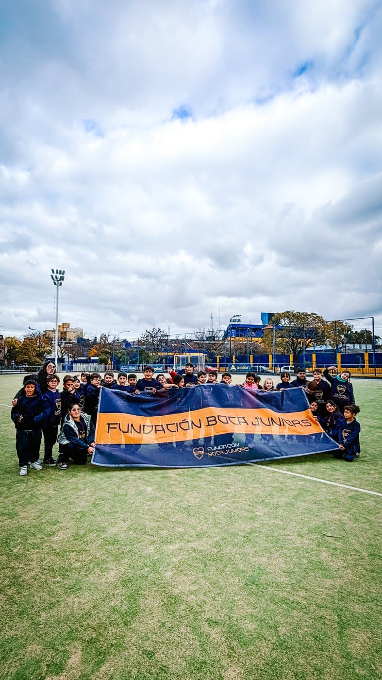 Foto grupal del contingente con la bandera de la Fundación en la cancha