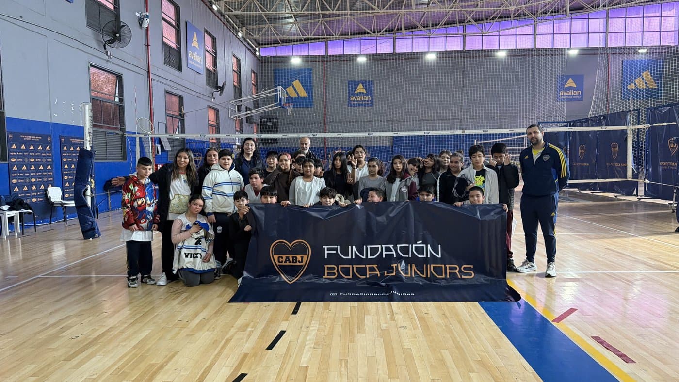El grupo completo posa en el gimnasio detrás de la bandera de la Fundación, junto a la red de vóley