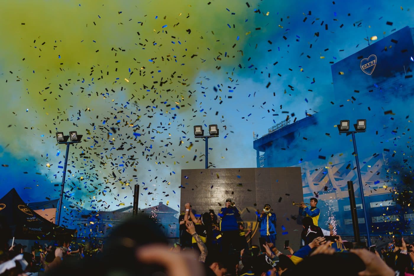 Lluvia de papelitos azules y dorados sobre el escenario y la multitud, al atardecer