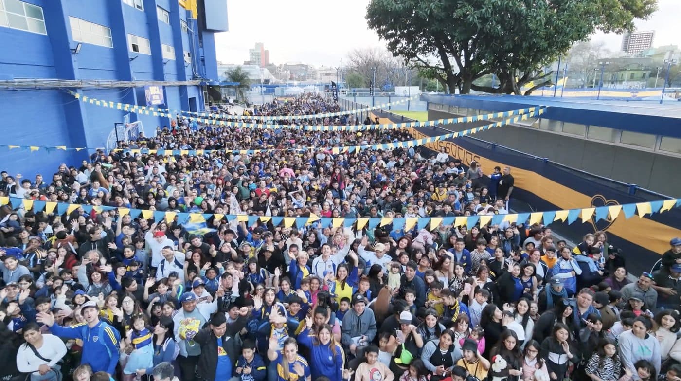La calle repleta de familias bajo los banderines azules y blancos, junto al paredón del club