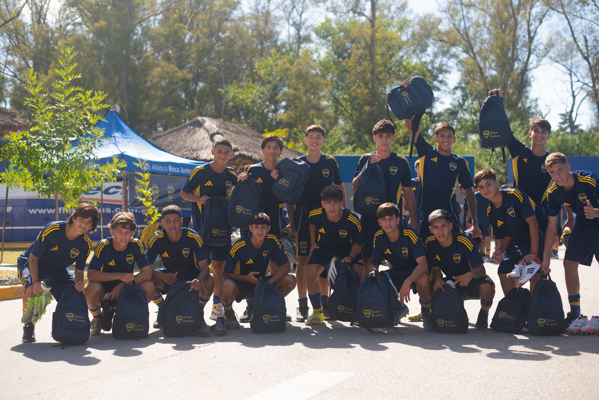Adolescentes con indumentaria de Boca sosteniendo las mochilas entregadas por la Fundación, en una jornada al aire libre