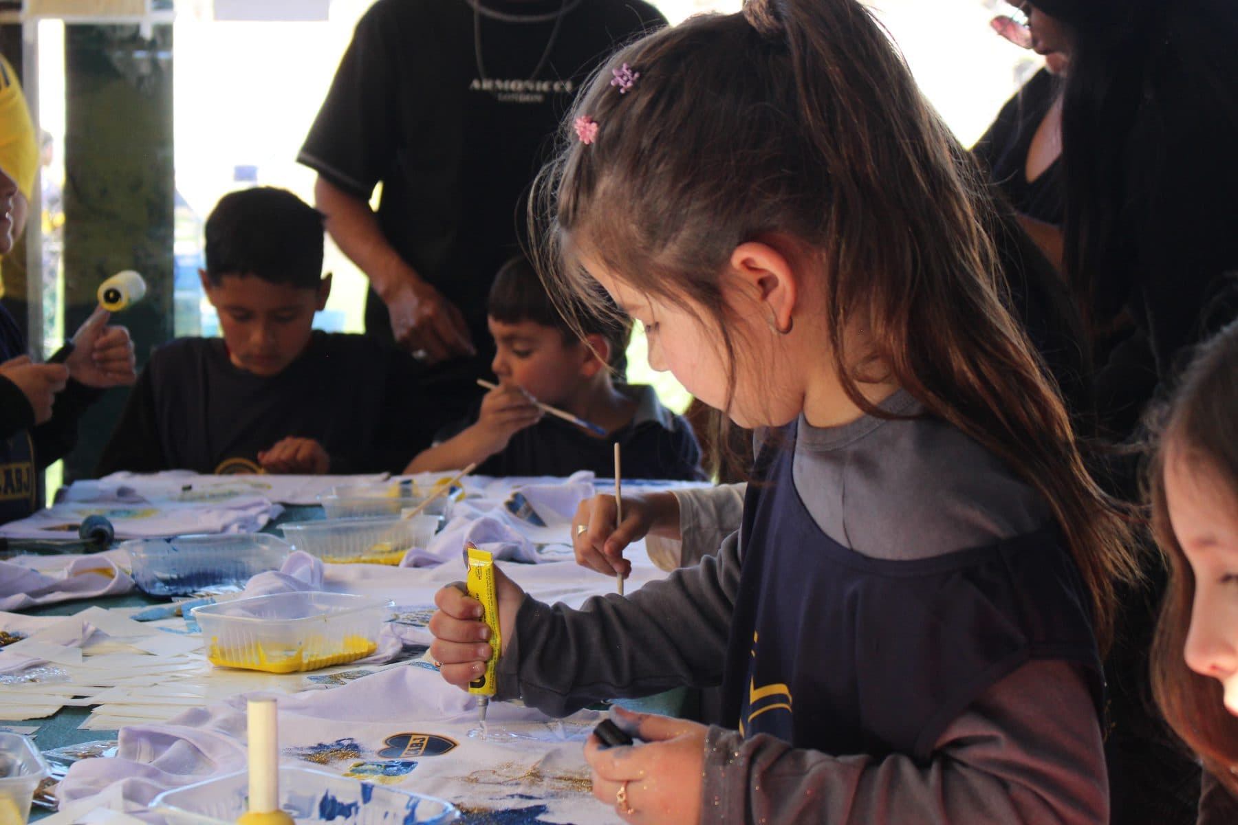 Chicos y chicas pintando sus camisetas con pinceles sobre las mesas del taller, en Córdoba