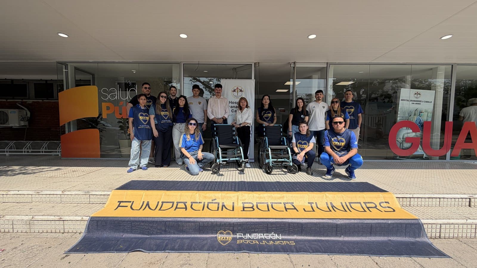 El equipo de la Fundación junto a las autoridades del hospital, con las sillas de ruedas donadas y el banner de la Fundación en la entrada