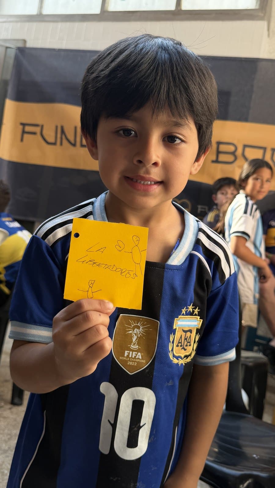 Un chico con la camiseta de Boca sostiene la pieza que pintó durante la jornada