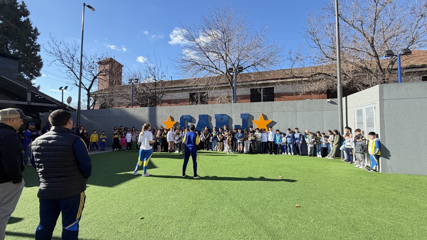 Ronda de chicos y chicas en la cancha de césped sintético, frente al mural del CABJ