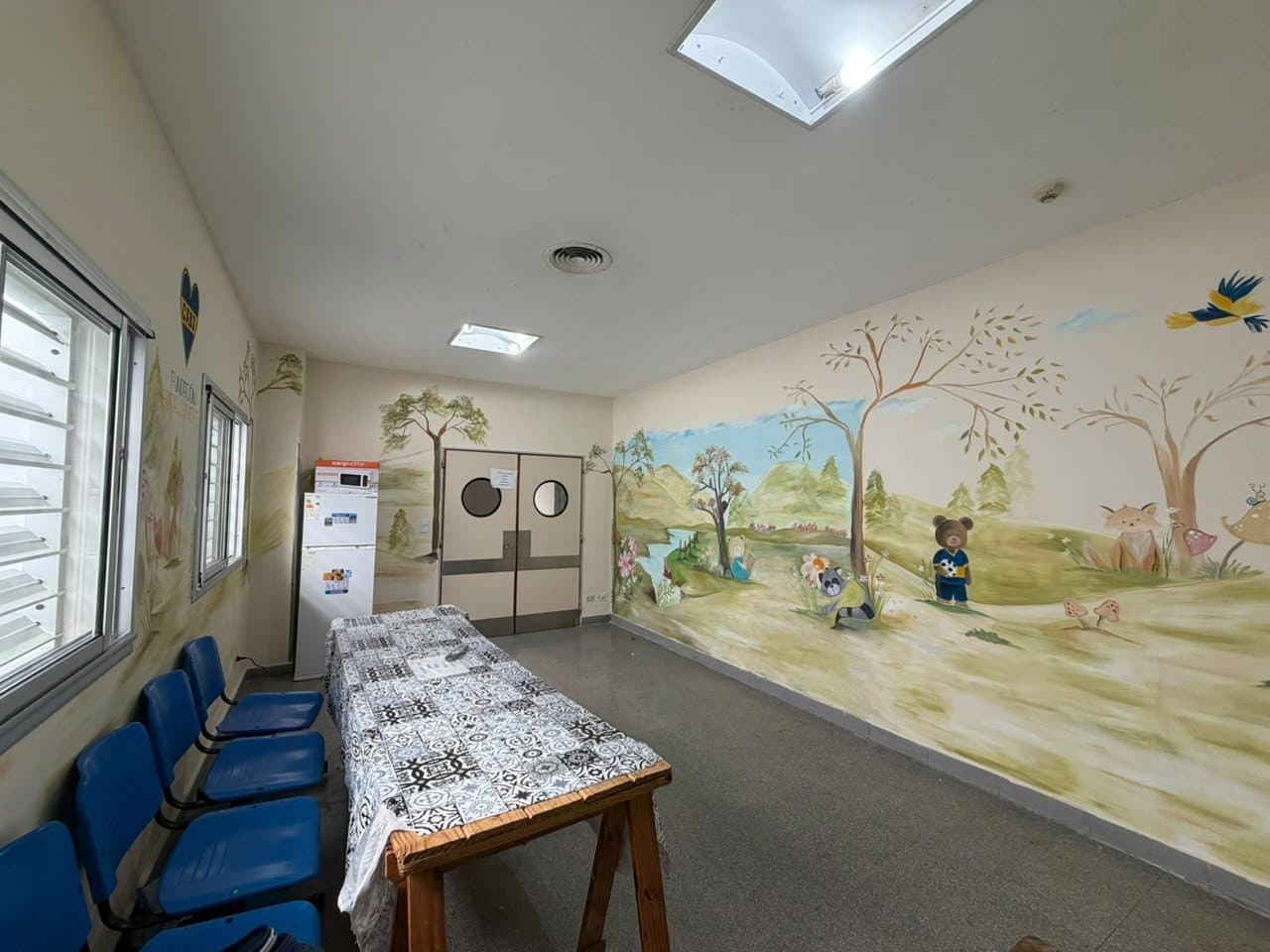 Sala del estar de padres con el mural de Claudia Domínguez y sillas para las familias