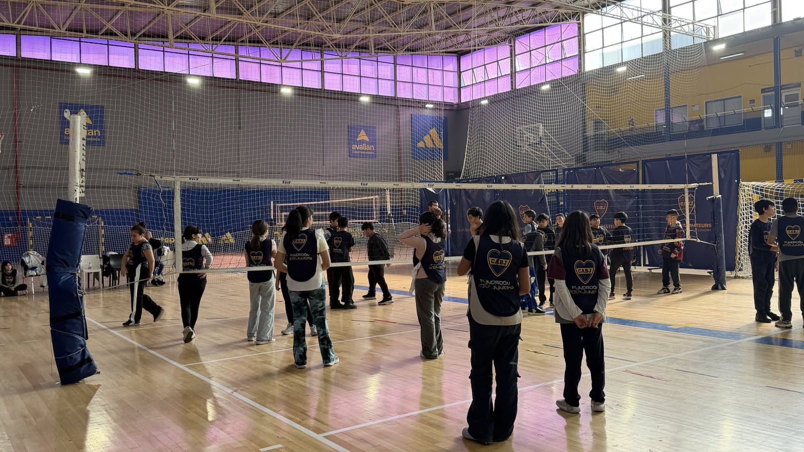 Clínica de vóley en el gimnasio del club, con chicos y chicas a ambos lados de la red