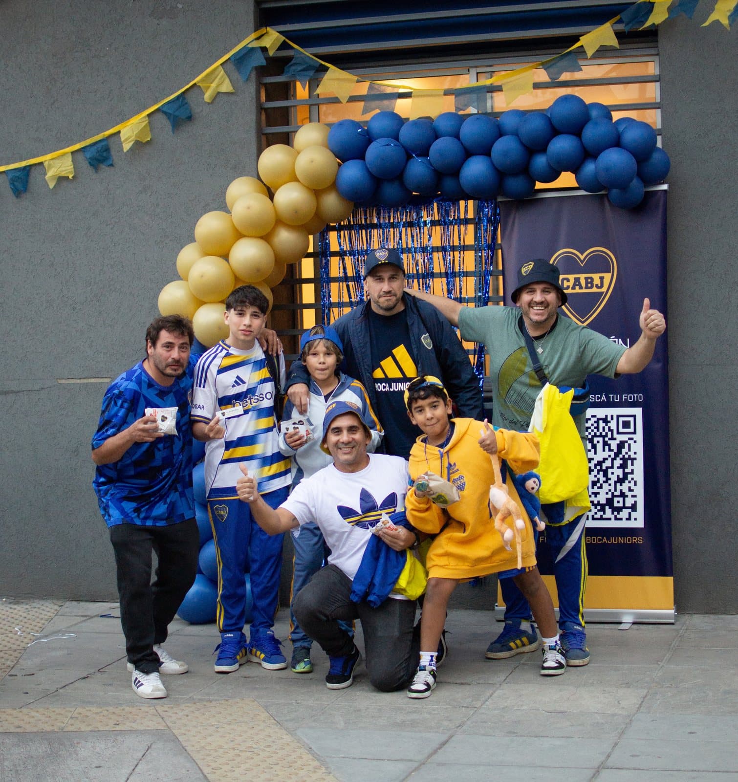 Una familia posando en el spot de fotos de la Fundación, junto a un arco de globos azules y dorados