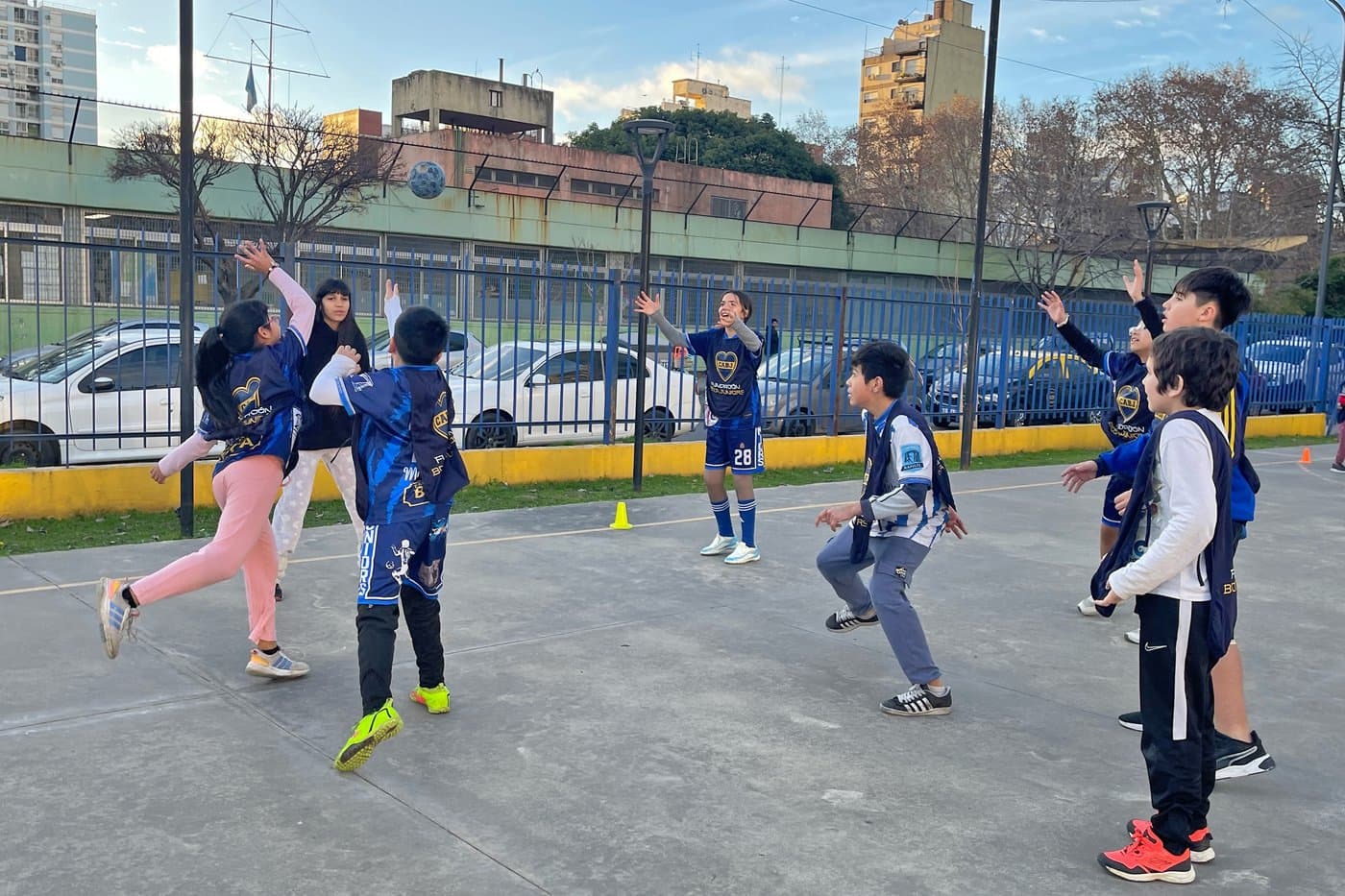 Chicos y chicas saltando con los brazos en alto durante un ejercicio en la cancha