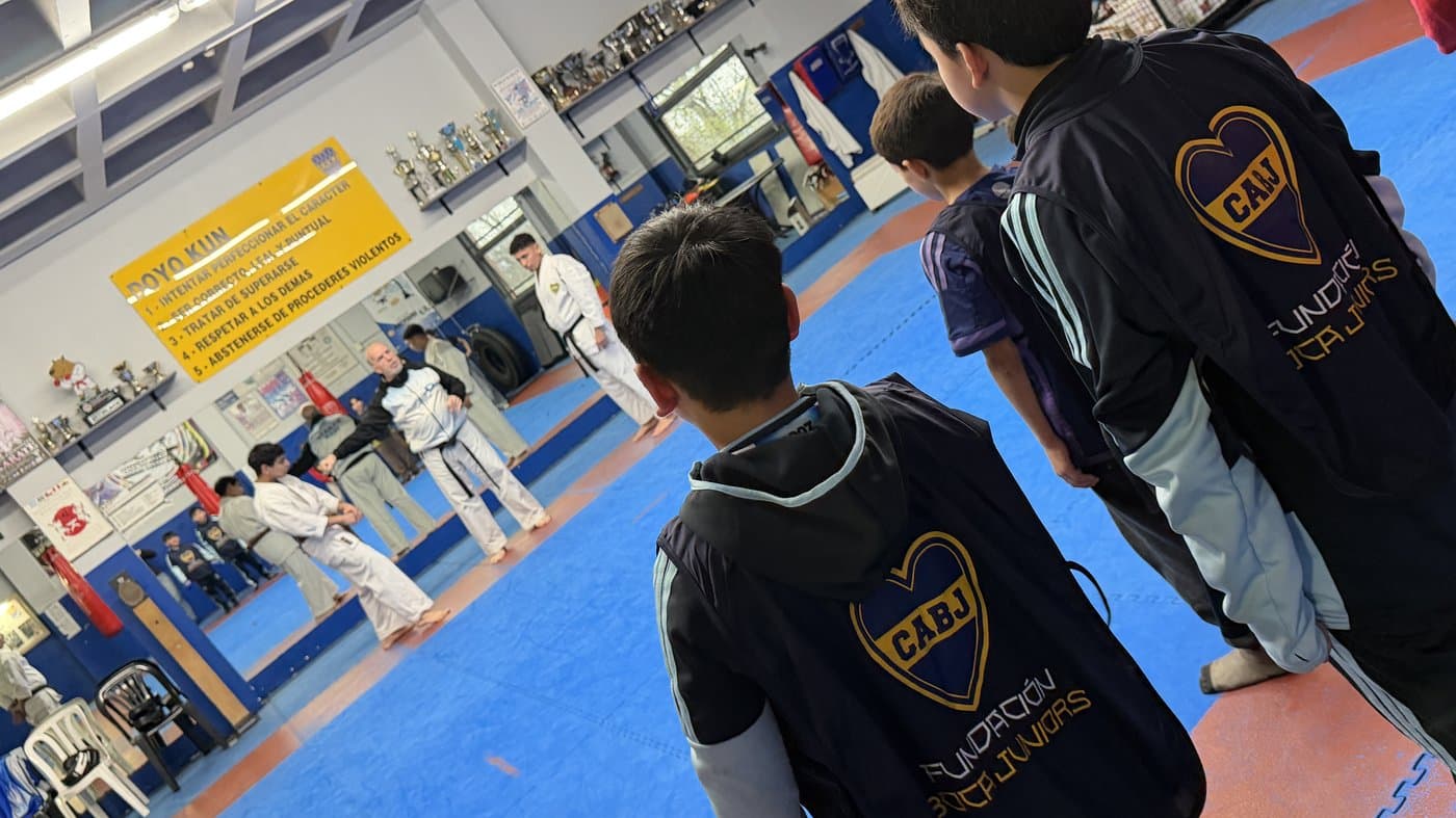 Chicos con la pechera de la Fundación siguen la demostración en el dojo
